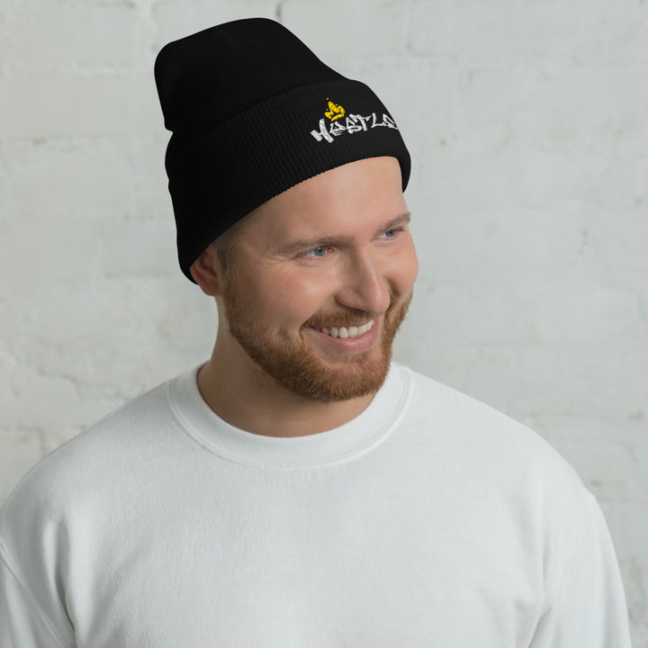 A modern man in a studio is wearing the Embroidered Hustle King Theme Cuffed Beanie.