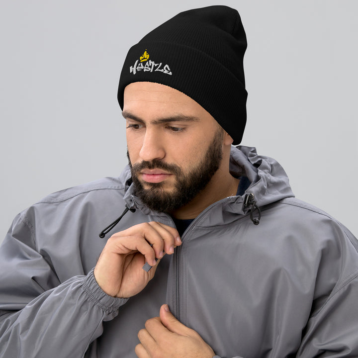 A modern man zipping his jacket is wearing the Embroidered Hustle King Theme Cuffed Beanie.