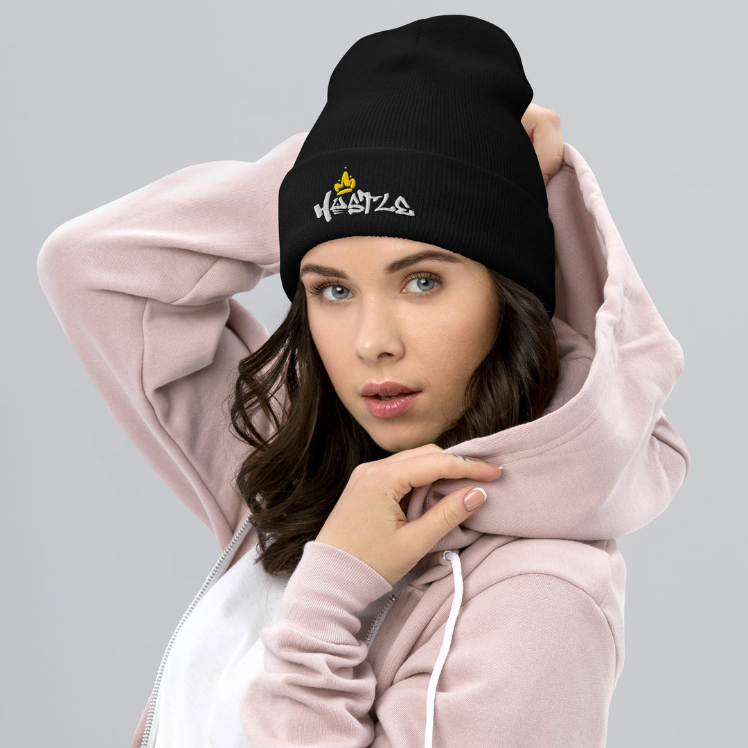 A modern woman in a jacket is wearing the Embroidered Hustle King Theme Cuffed Beanie.