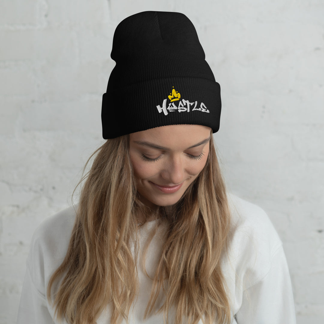 A modern woman in a studio is wearing the Embroidered Hustle King Theme Cuffed Beanie.