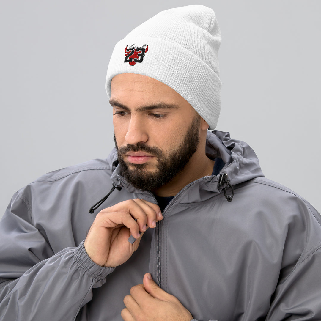 A young man zipping his jacket is wearing the Legend 23 And Tribute Embroidered Cuffed Beanie, front view..