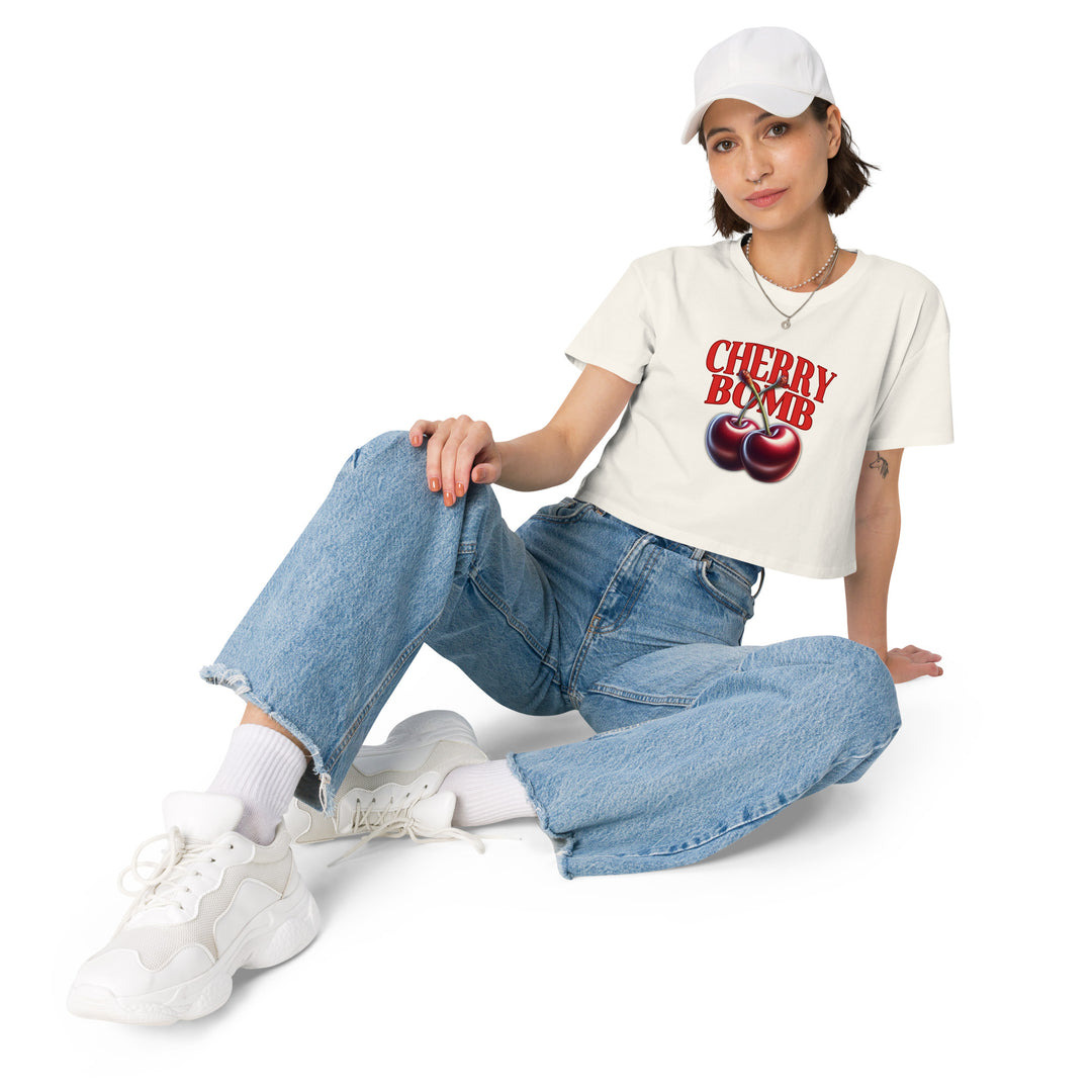 A young woman is wearing the Women’s Cherry Bomb Graphic Crop Top, front view.