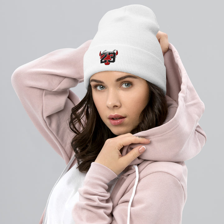 A young woman wearing a jacket is wearing the Legend 23 And Tribute Embroidered Cuffed Beanie, front view.
