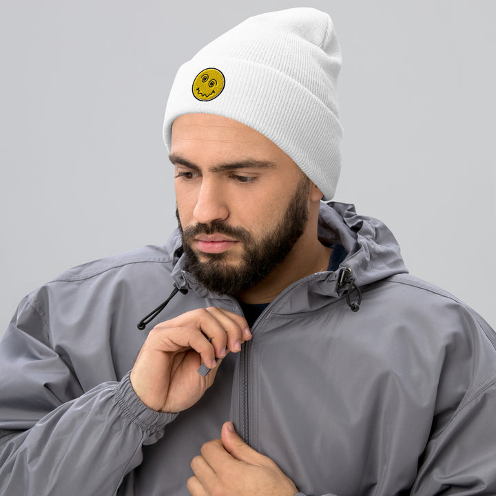 An urban man in the studio is wearing the Embroidered Anxiety Face Cuffed Beanie, front view.