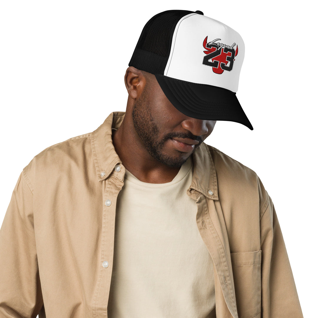 An urban man is wearing the Legend 23 Embroidered Black And White Foam Trucker Hat, front view.