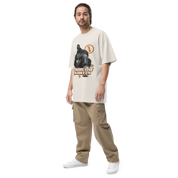An urban man is wearing the Men's I Own The Streets Theme Oversized Faded Tee, front left view.